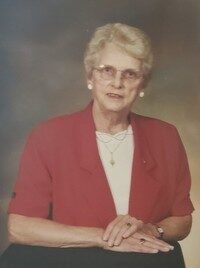 Elderly woman in red jacket posing for portrait.