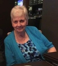 Elderly woman in blue sweater smiling at restaurant