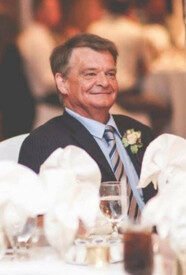 Smiling man in suit at formal event table.