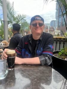 Person enjoying a pint on a sunny patio.