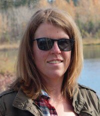 Person outdoors wearing sunglasses smiling near water