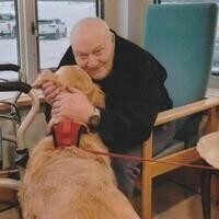 Man hugging a golden retriever inside home