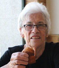 Smiling elderly woman holding a muffin.