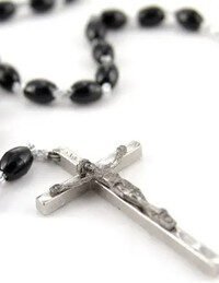 Rosary beads with silver crucifix on white background.