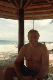 Man relaxing under beach pavilion by the sea.