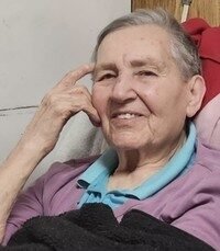Elderly person smiling while seated indoors.