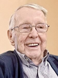 Elderly man smiling joyfully at camera.