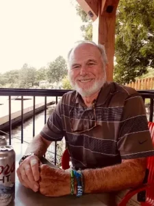Smiling man sitting outdoors with drink.