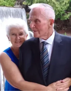Elderly couple embracing near a waterfall.