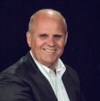 Smiling bald man in dark suit and white shirt.