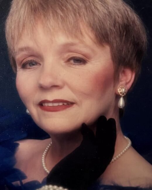 Woman wearing pearl earrings and necklace, smiling softly.