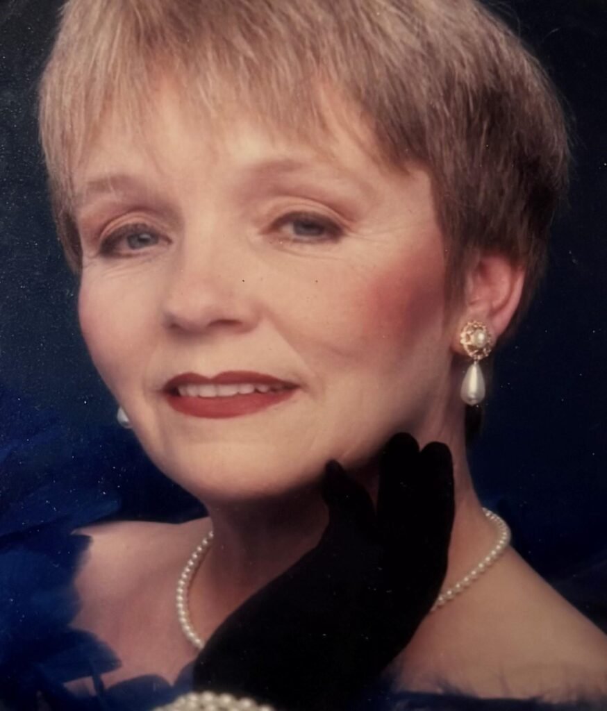 Woman wearing pearl earrings and necklace, smiling softly.