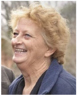 Smiling person outdoors with short hair and jacket.