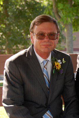 Man in suit with sunglasses and flower boutonniere.