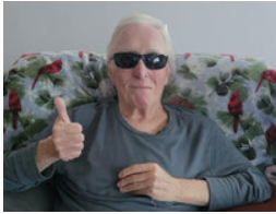 Smiling man in sunglasses giving thumbs-up.