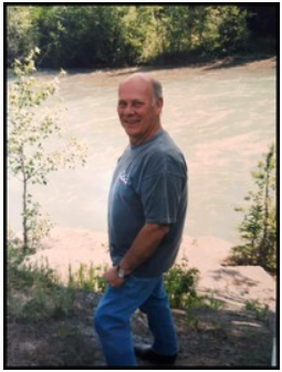 Man standing by a river, smiling.