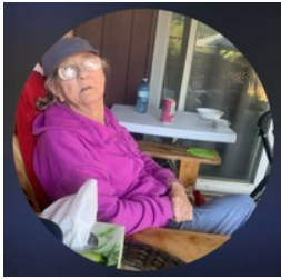 Person in pink hoodie sitting outside on deck.