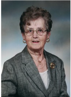 Elderly woman in gray suit with glasses smiling.