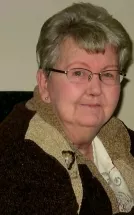 Elderly woman wearing glasses and a warm jacket.