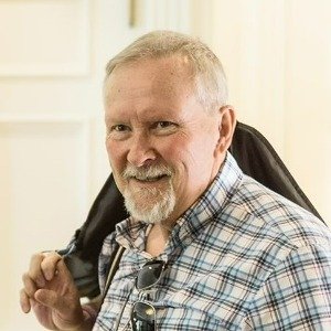 Smiling man with beard and glasses indoors.