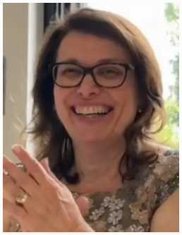 Smiling woman clapping with glasses indoors.