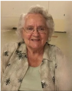 Smiling elderly woman with glasses and white hair.