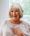 Smiling elderly woman with white hair indoors.