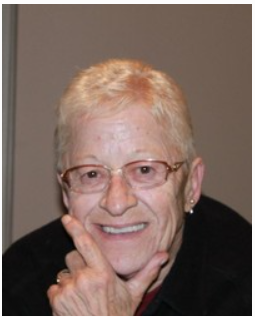 Smiling person with short hair and glasses.