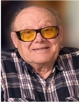 Smiling man with yellow glasses and plaid shirt.