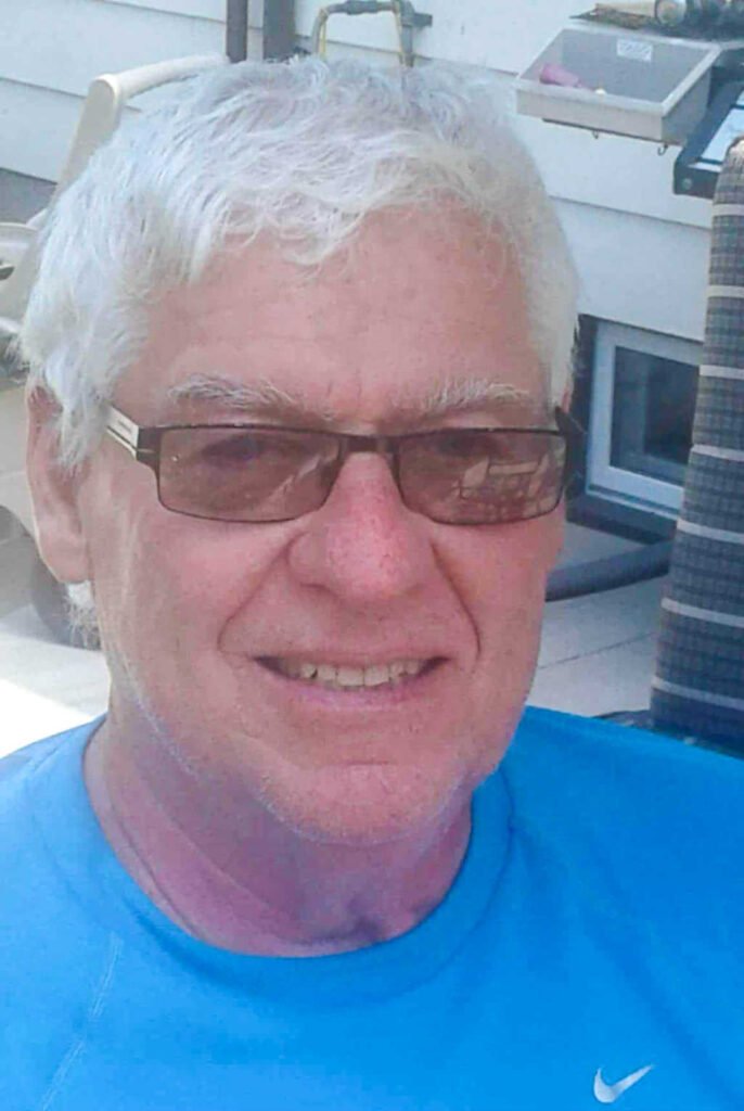 Smiling man with glasses and white hair.