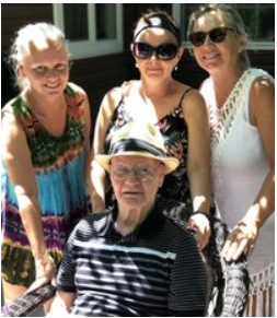 Four adults posing outside, smiling together.