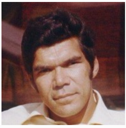 Man with dark hair and sideburns outdoors.