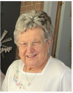 Smiling elderly woman with gray hair and glasses.