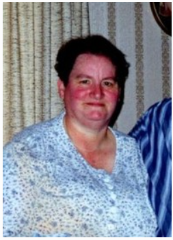 Person smiling in patterned blouse indoors.