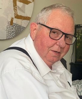 Elderly man with glasses and white shirt.