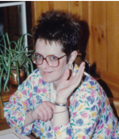 Person smiling, wearing colorful floral outfit indoors.