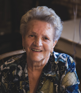 Smiling elderly woman in blue patterned shirt.