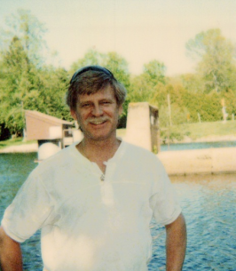 Smiling person by a riverside in sunlight