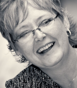 Smiling person wearing glasses and earrings.