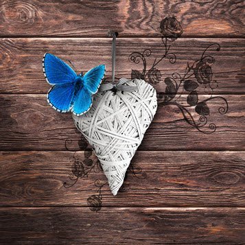 Blue butterfly on yarn heart with wooden background.