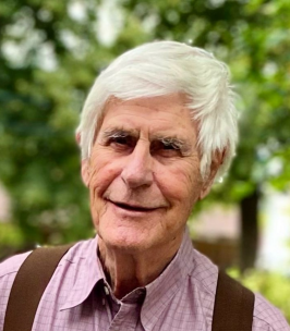 Elderly man with white hair and suspenders smiling