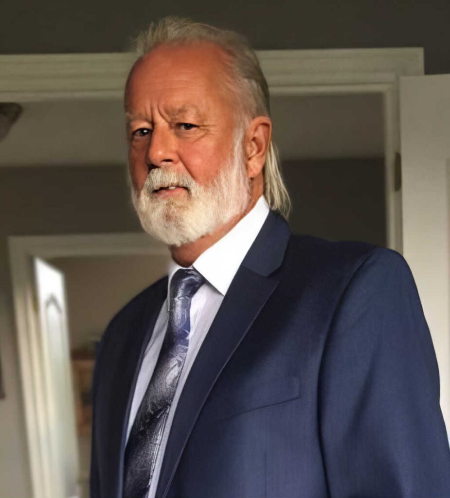 Elderly man in a suit with white beard.