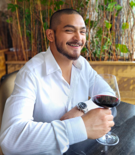 Smiling man enjoying red wine at a restaurant.
