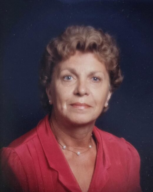 Woman wearing red blouse, pearl necklace, studio portrait.