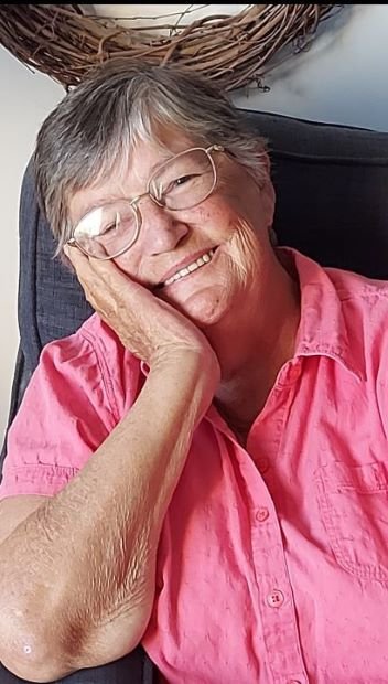 Smiling woman in pink shirt and glasses.