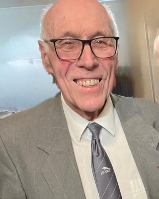 Elderly man smiling in a gray suit