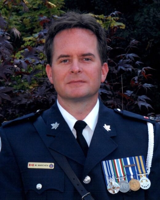 Uniformed officer with medals outdoors.