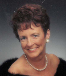 Smiling woman wearing pearls and a black dress.