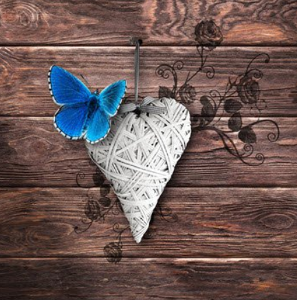 Blue butterfly on wooden heart decoration.