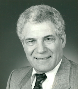 Smiling elderly man in gray suit and tie.